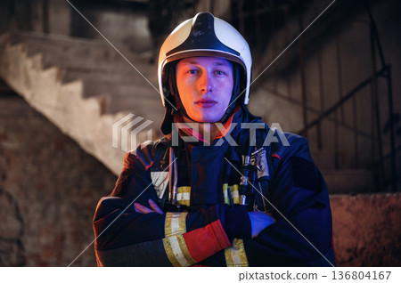 Looking forward, standing. Firefighter in professional equipment is indoors in abandoned building 136804167