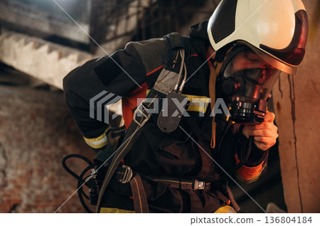 Hard to breathe, using air mask. Firefighter in professional equipment is indoors in abandoned building Hard to breathe, using air mask. Firefighter in professional equipment is indoors in abandoned building 136804184