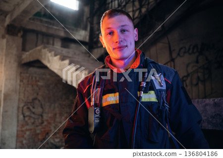 Looking forward, standing. Firefighter in professional equipment is indoors in abandoned building Looking forward, standing. Firefighter in professional equipment is indoors in abandoned building 136804186