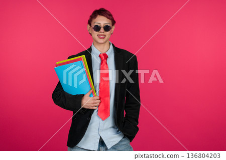 Confident young person holding folders smiling at camera Confident young person holding folders smiling at camera 136804203