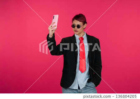 Young person taking selfie with smartphone on pink background 136804205