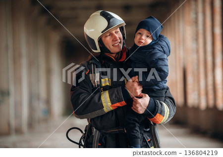 Firefighter is with baby boy indoors 136804219