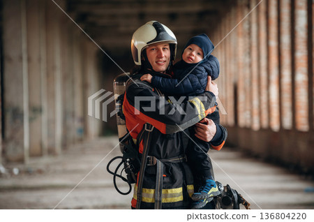 Firefighter is with baby boy indoors 136804220