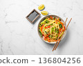 Vegetarian wok noodles with vegetables and lime in a plate on a light marble background 136804256