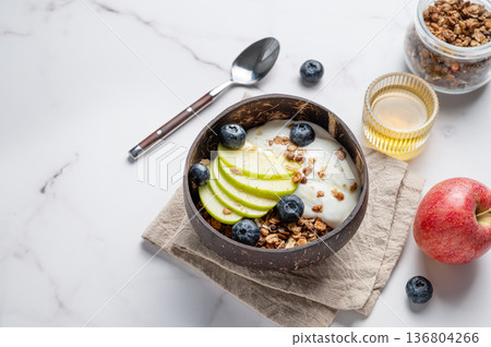 Natural greek yogurt with granola, blueberry and apple in a bowl on a marble background Natural greek yogurt with granola, blueberry and apple in a bowl on a marble background 136804266