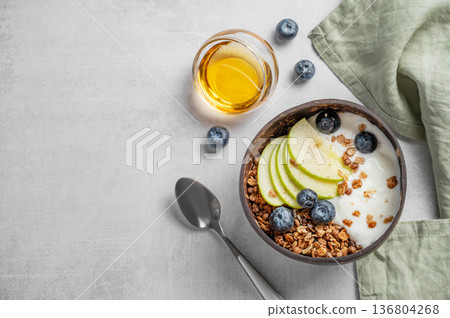 Natural greek yogurt with granola, blueberry and apple in a bowl on a light background with honey Natural greek yogurt with granola, blueberry and apple in a bowl on a light background with honey 136804268