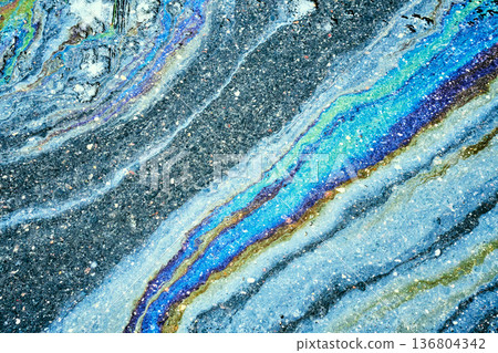 Iridescent oil slick creating abstract rainbow pattern on asphalt. Iridescent oil slick creating abstract rainbow pattern on asphalt. 136804342