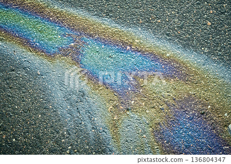 Oil Spill on Pavement Showing Colors in Sunlight After Rain Near a Parking Lot in the Afternoon Oil Spill on Pavement Showing Colors in Sunlight After Rain Near a Parking Lot in the Afternoon 136804347