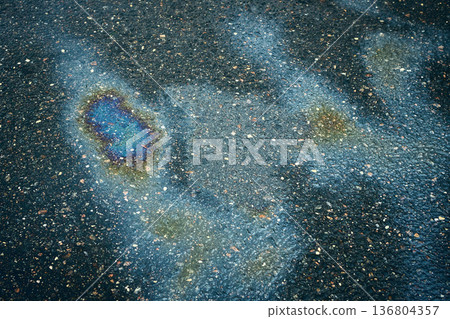 Colorful oil or gasoline stain creating stunning iridescent patterns on the soaked asphalt. Colorful oil or gasoline stain creating stunning iridescent patterns on the soaked asphalt. 136804357