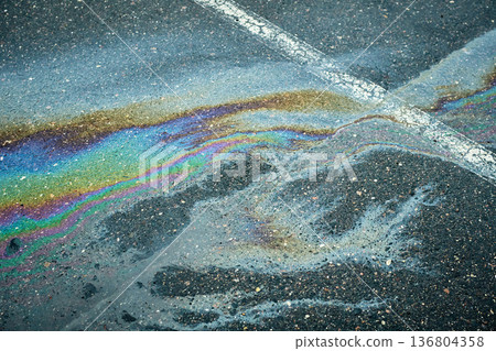 Bright oil spill forming mesmerizing rainbow hues on the wet asphalt after rain Bright oil spill forming mesmerizing rainbow hues on the wet asphalt after rain 136804358