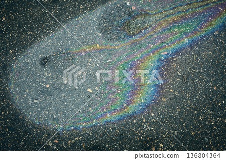 Bright oil stain creating captivating iridescent hues on the soaked asphalt surface. Bright oil stain creating captivating iridescent hues on the soaked asphalt surface. 136804364