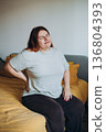 Sad Woman complaining suffering back ache sitting on uncomfortable bad at home 136804393