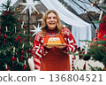 Happy smiling young 30s woman with gingerbread standing by the New Year tree. Merry Christmas, Happy Holidays banner. 136804521