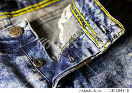 Denim fabric details. Textured blue denim with yellow stitching and metal hardware details Denim fabric details. Textured blue denim with yellow stitching and metal hardware details 136804546