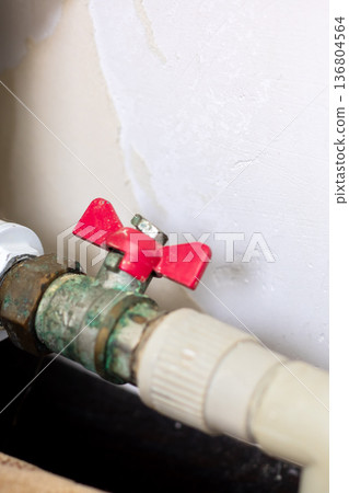 Technician inspecting heavily corroded water valve and hose fitting for repair needs 136804564