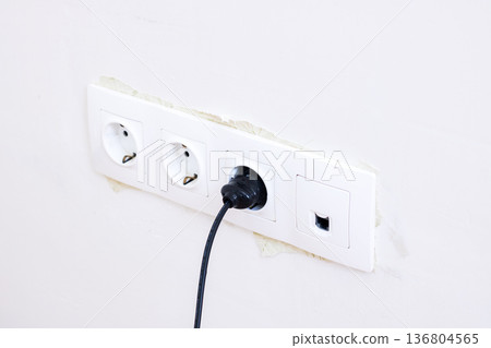 Focus on household power outlet with chipped paint and pluggedin cable in minimal decor 136804565