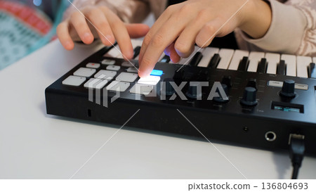 Close-up of teen girl enjoys making music at home with midi keyboard while wearing headphones and sunglasses, expressing her creativity 136804693
