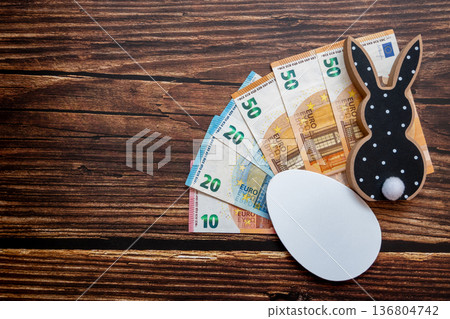 Black and white wood rabbit and egg with cash euro money for easter celebration on the wood background. Shopping of Easter holidays. Space for text. 136804742