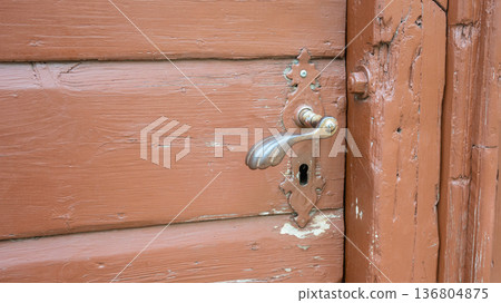 Old wood door with metal handle and keyhole. Vintage iron pen. House entrance. 136804875