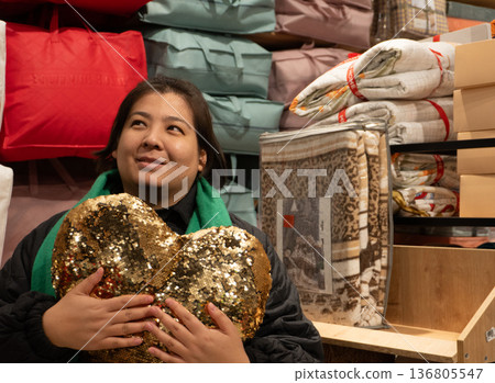 Woman Holding Sequin Heart Pillow in Bedding Store Woman Holding Sequin Heart Pillow in Bedding Store 136805547