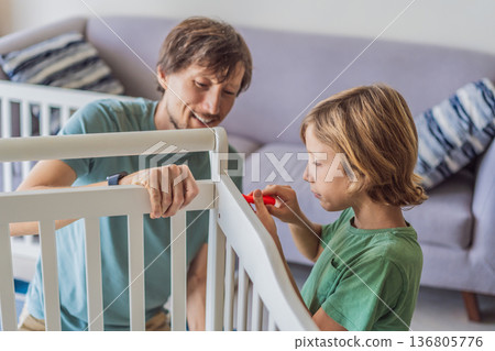 Father and older brother assembling a baby crib at home, preparing for a newborn arrival. Warm family moment full of care and anticipation. Parenthood, sibling bond and home preparation concept 136805776