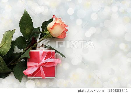Greeting card for Women's Day or Valentine's Day. Red rose and gift box on abstract blurred background with bokeh. March 8 festive background, place for text, banner. Happy birthday, wedding. Spring Greeting card for Women's Day or Valentine's Day. Red rose and gift box on abstract blurred background with bokeh. March 8 festive background, place for text, banner. Happy birthday, wedding. Spring 136805841