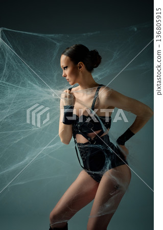 Gothic fashion concept of a woman in black lingerie trapped in spiderwebs. Gothic fashion concept of a woman in black lingerie trapped in spiderwebs. 136805915