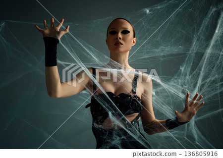 Powerful woman with dramatic black eye makeup trapped in a spooky spiderweb 136805916
