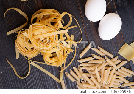 variety of types and shape of italian pasta with eggs on dark wooden table. cooking  background. close up 136805976