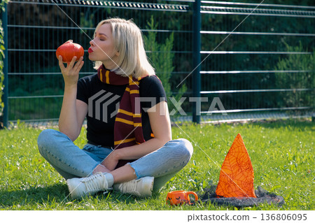 A beautiful girl is sitting on the terrace with a dog, holding a pumpkin in her hand. A beautiful girl is sitting on the terrace with a dog, holding a pumpkin in her hand. 136806095