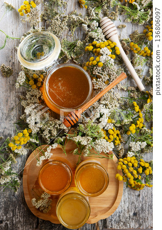 fresh natual different  honey in glass jars with wooden  honey spoons around herb flowers. flat lay 136806097