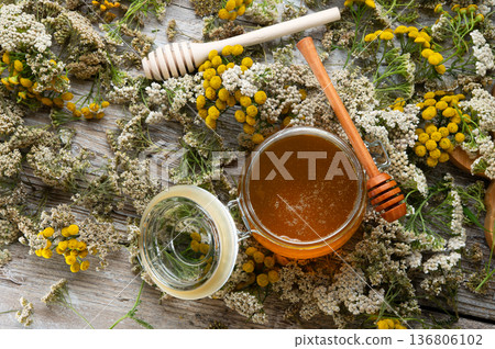 fresh natual honey in glass jar with wooden honey spoons around herb flowers. flat lay fresh natual honey in glass jar with wooden honey spoons around herb flowers. flat lay 136806102