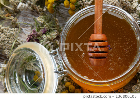 fresh natual honey in glass jar with wooden  honey spoons around herb flowers. macro 136806103