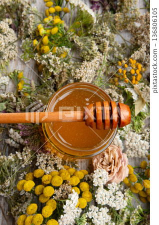 fresh natual honey in glass jar with wooden honey spoons around herb flowers. macro fresh natual honey in glass jar with wooden honey spoons around herb flowers. macro 136806105