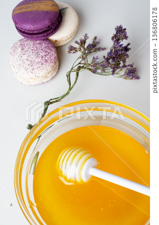 linden fresh honey with spoon on white background with blossoming  herb and  macaroons.  top view 136806178