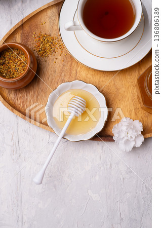 linden honey with perga and cup of tea at wooden tray on white table.  top view 136806189