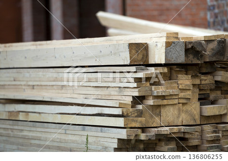 Stack of natural brown uneven rough wooden boards on building site. Industrial timber for carpentry, building, repairing and furniture, lumber material for roofing construction. Stack of natural brown uneven rough wooden boards on building site. Industrial timber for carpentry, building, repairing and furniture, lumber material for roofing construction. 136806255