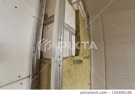 Metal frame for future walls with drywall plates insulated with rock wool and fiberglass insulation staff for cold barrier. Comfortable warm home, economy, construction and renovation concept. 136806286