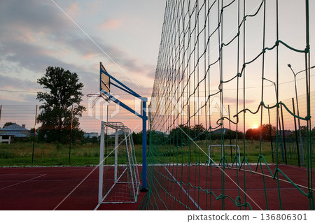 Outdoors mini football and basketball court with ball gate and basket surrounded with high protective fence. Outdoors mini football and basketball court with ball gate and basket surrounded with high protective fence. 136806301