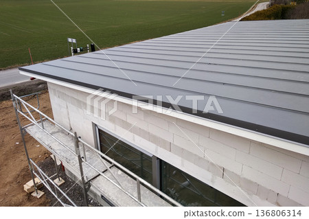 Facade of building made from white blocks with big windows under construction works. Facade of building made from white blocks with big windows under construction works. 136806314