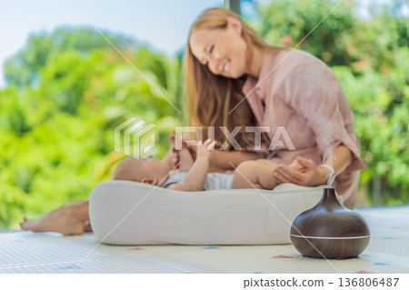 Newborn baby resting in a cozy cocoon beside mother with aroma lamp, calm home atmosphere. Infant relaxation, gentle care, motherhood routine, aromatherapy for babies and family wellbeing concept. Newborn baby resting in a cozy cocoon beside mother with aroma lamp, calm home atmosphere. Infant relaxation, gentle care, motherhood routine, aromatherapy for babies and family wellbeing concept. 136806487