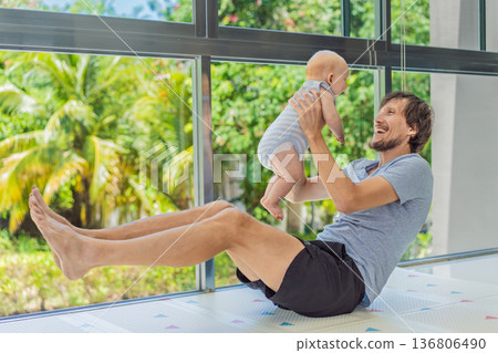 Father exercising with his small baby at home, active parenting and healthy lifestyle. Strong family bond, early physical development, modern fatherhood, fitness with children concept. Father exercising with his small baby at home, active parenting and healthy lifestyle. Strong family bond, early physical development, modern fatherhood, fitness with children concept. 136806490
