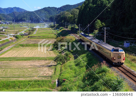 A Sanin Main Line express train runs past rice fields in the off-season heading towards Kinosaki 136806648