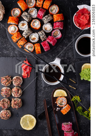 different sushi rolls set with fish and shiitake mushrooms served at black dishes at black table. flat lay different sushi rolls set with fish and shiitake mushrooms served at black dishes at black table. flat lay 136806883