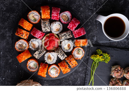 different sushi rolls set with fish and shiitake mushrooms beautiful served at black dishes at black table. flat lay different sushi rolls set with fish and shiitake mushrooms beautiful served at black dishes at black table. flat lay 136806888