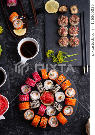 different sushi rolls set with fish and shiitake mushrooms beautiful served at black dishes at black table. flat lay different sushi rolls set with fish and shiitake mushrooms beautiful served at black dishes at black table. flat lay 136806889