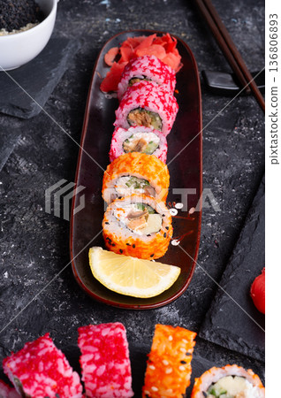 different delicious sushi rolls set with fish beautiful served at black dish at black table. close up different delicious sushi rolls set with fish beautiful served at black dish at black table. close up 136806893