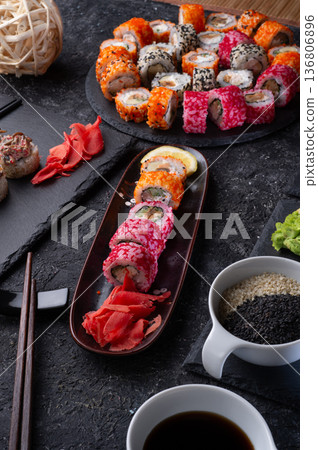 different sushi rolls set with fish served at black dish at black table. different sushi rolls set with fish served at black dish at black table. 136806896
