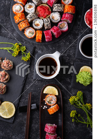 different sushi rolls set with fish and shiitake mushrooms beautiful served at black dishes at black table. flat lay different sushi rolls set with fish and shiitake mushrooms beautiful served at black dishes at black table. flat lay 136806898