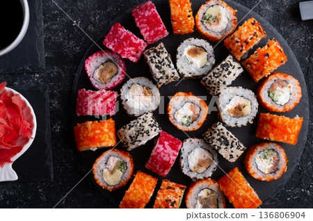 different delicious sushi rolls set with fish served at black dish at black table. flat lay. close up different delicious sushi rolls set with fish served at black dish at black table. flat lay. close up 136806904